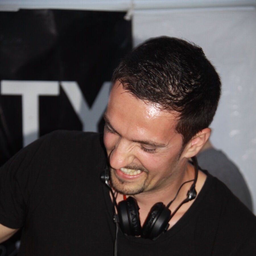 DEEP UNIT smiling in a black T-shirt during a night set